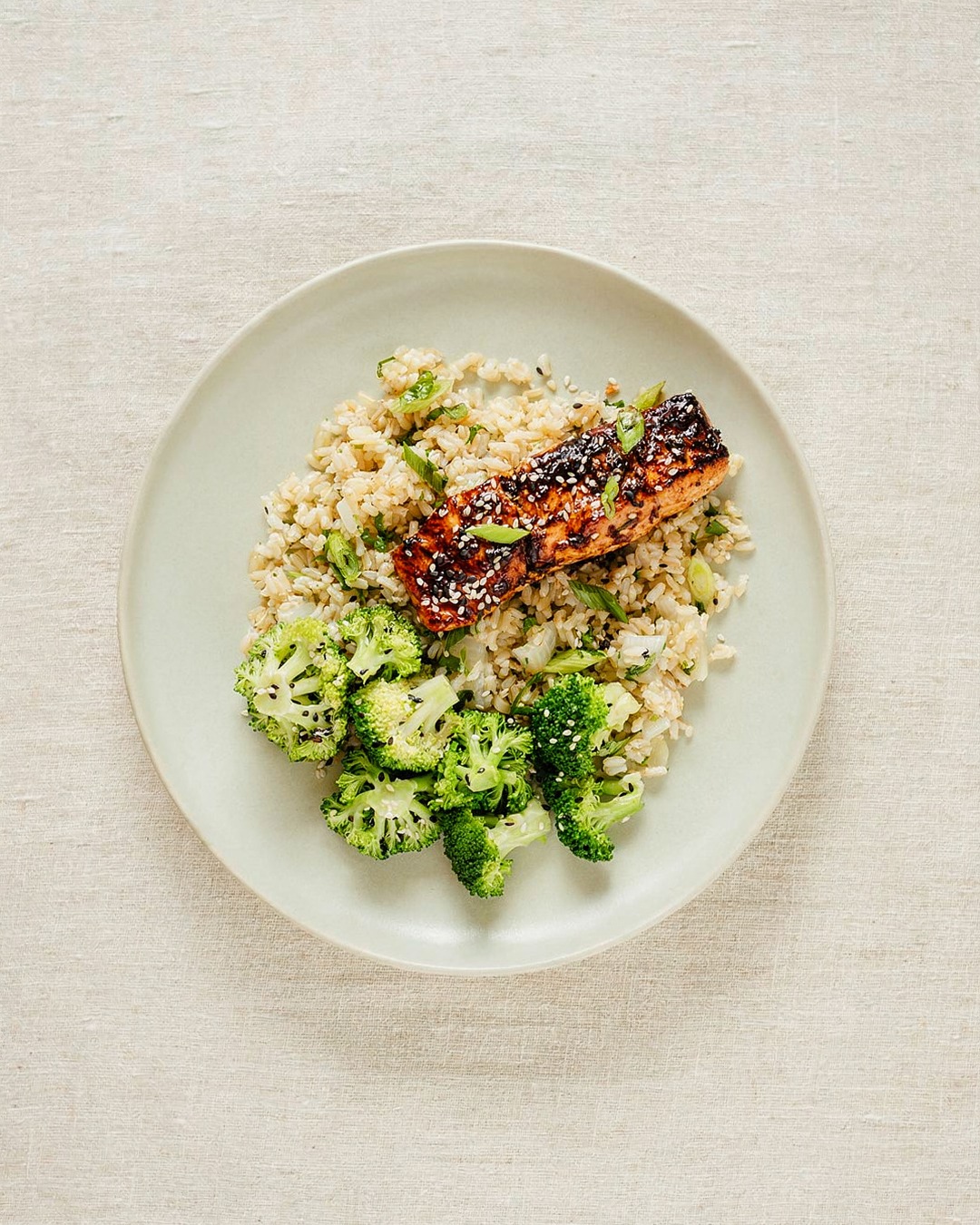 Overhead plate of Territory salmon with broccoli and grains on a cream table